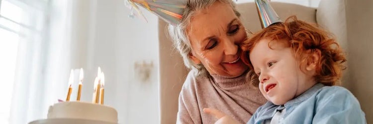 Image of a grandmother looking at a child blowing out candles on a cake (not actual patients)