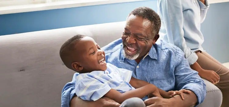 Image of an older man smiling and playing with a child (not actual patients) mobile