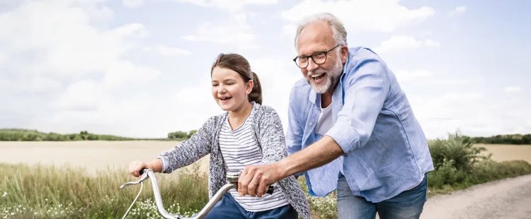 Image of an older man helping a young girl ride a bike (not actual patients)