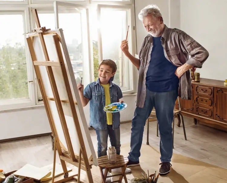 Image of an older man and a boy painting on an easel (not actual patients) mobile