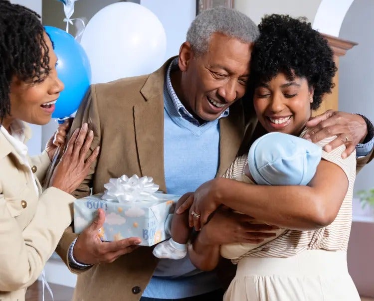 Image of a grandfather and grandmother looking at a mother holding a baby (not actual patients) mobile