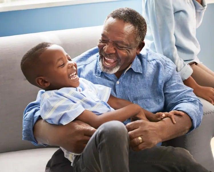 Image of an older man smiling and playing with a child (not actual patients) mobile