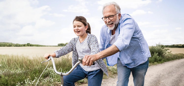 Image of an older man helping a young girl ride a bike (not actual patients)