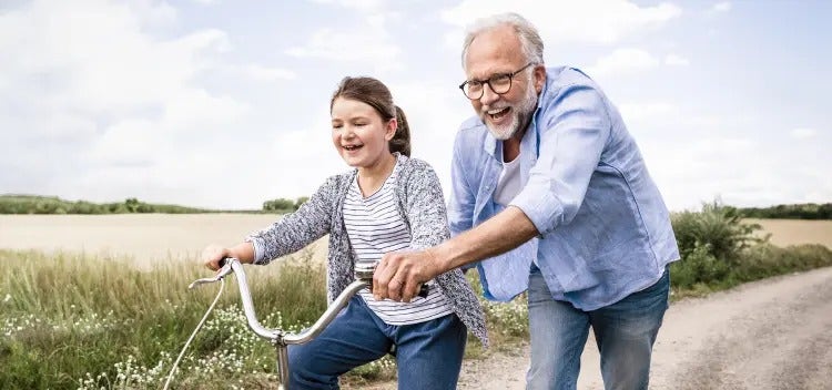 Image of an older man helping a young girl ride a bike (not actual patients) mobile