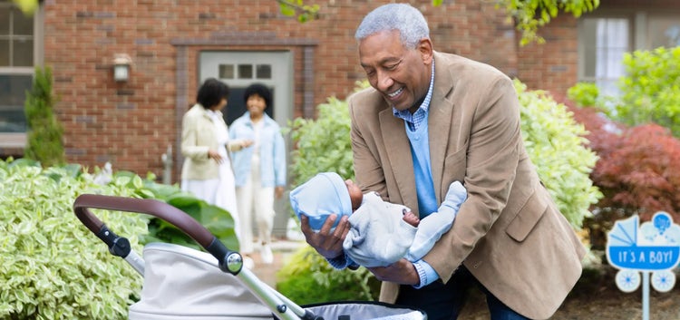 Image of a grandfather placing a baby in a carriage, as a grandmother and mother talk in the background (not actual patients)