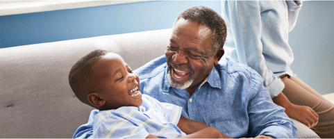 Image of an older man smiling and playing with a child (not actual patients)