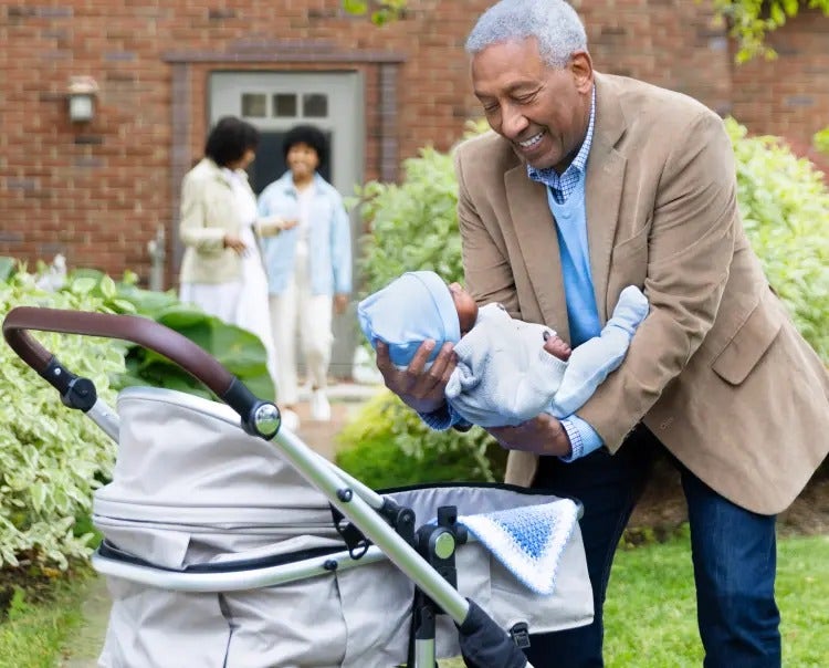 Image of a grandfather placing a baby in a carriage, as a grandmother and mother talk in the background (not actual patients) mobile