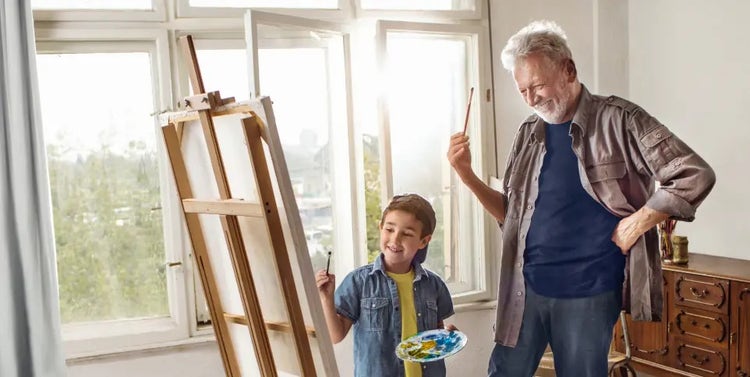 Image of an older man and a boy painting on an easel (not actual patients)