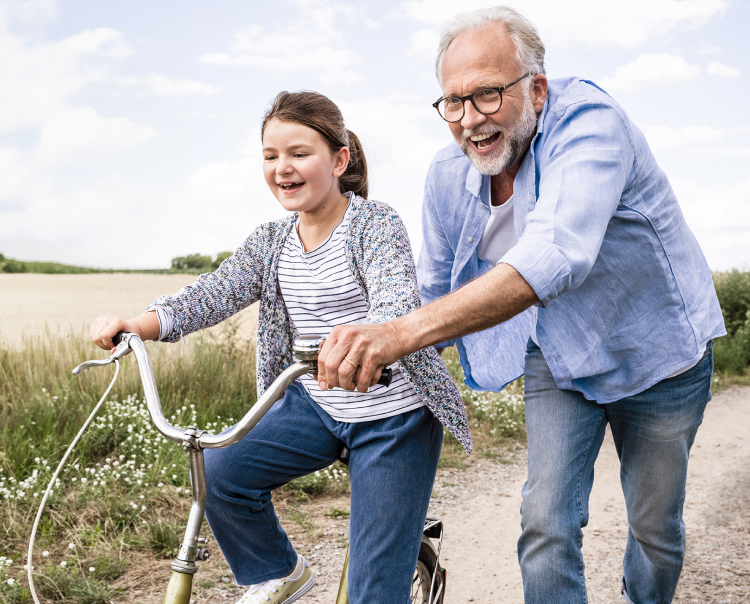 Image of an older man helping a young girl ride a bike (not actual patients) mobile