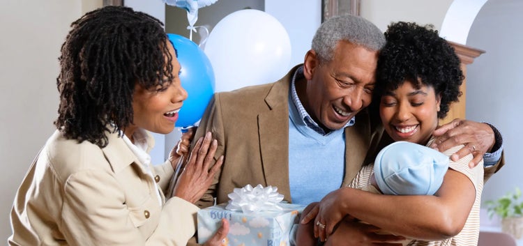 Image of a grandfather and grandmother looking at a mother holding a baby (not actual patients)