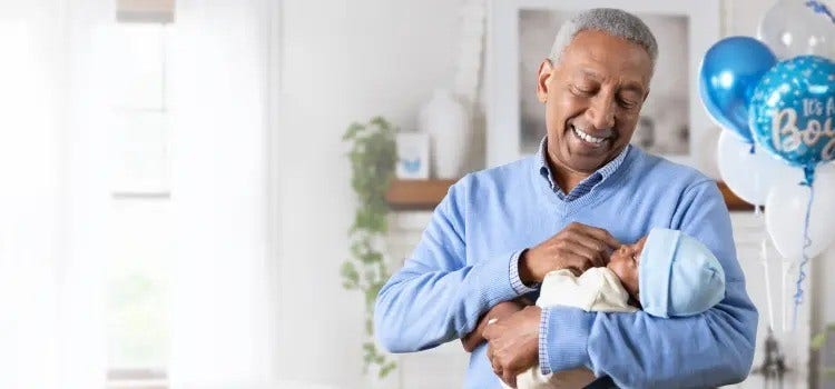 Image of a grandfather holding a baby (not actual patients) with blue balloons in background mobile