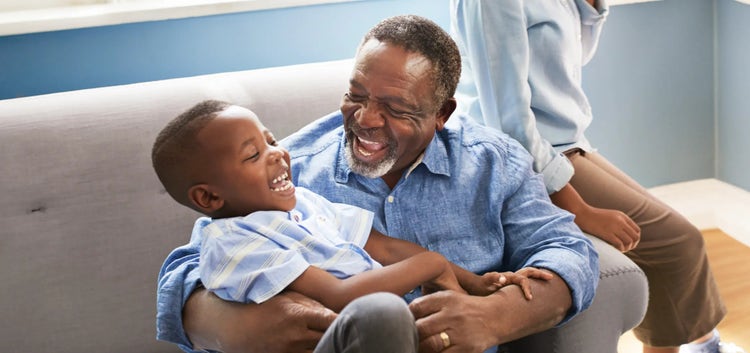 Image of an older man smiling and playing with a child (not actual patients)