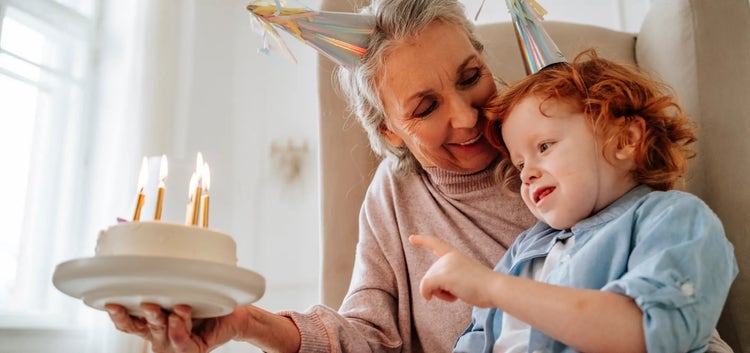 Image of a grandmother looking at a child blowing out candles on a cake (not actual patients)